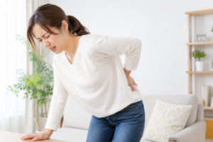 ぎっくり腰による急な腰の痛みで腰を押さえる女性